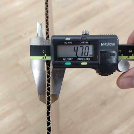 A vernier measuring the thickness of a cardboard sheet