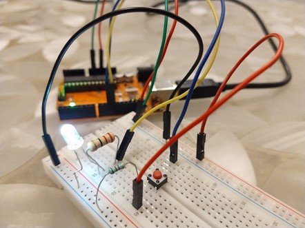 A breadboard with some wires, a button and a LED