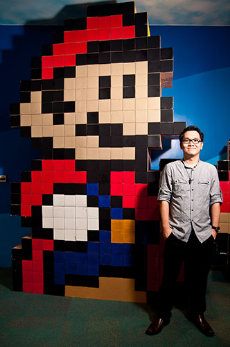 Bartholomew Ting beside a large pixel-style installation