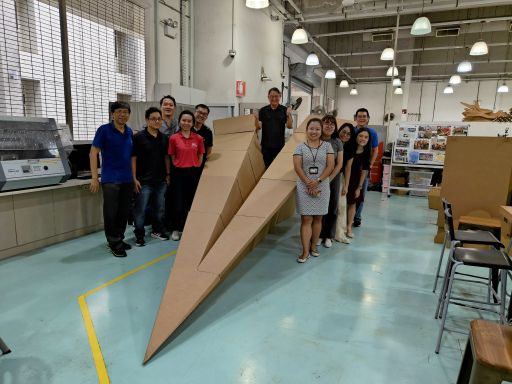 The fabrication team standing beside a four-metre cardboard paper airplane in the Fablab