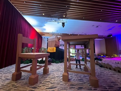 The oversized cardboard table and chair illuminated inside the exhibition hall