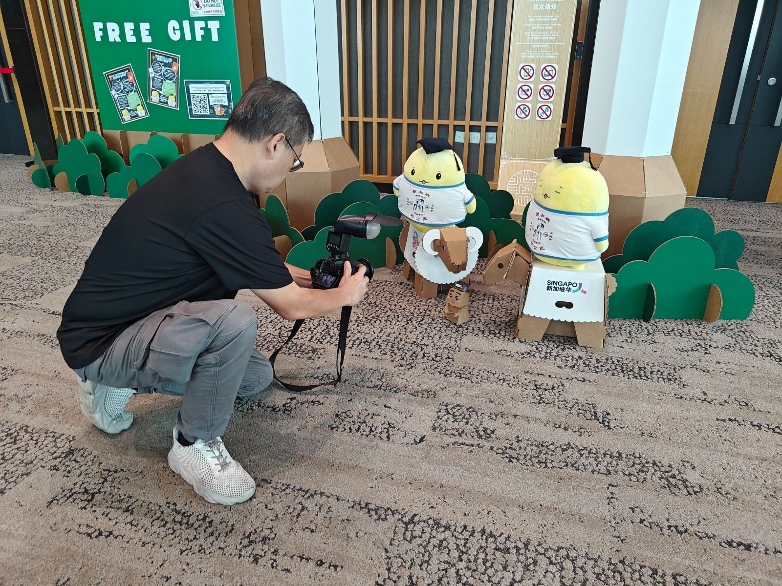 A visitor filming two interactive Teacher Kaki cardboard robots