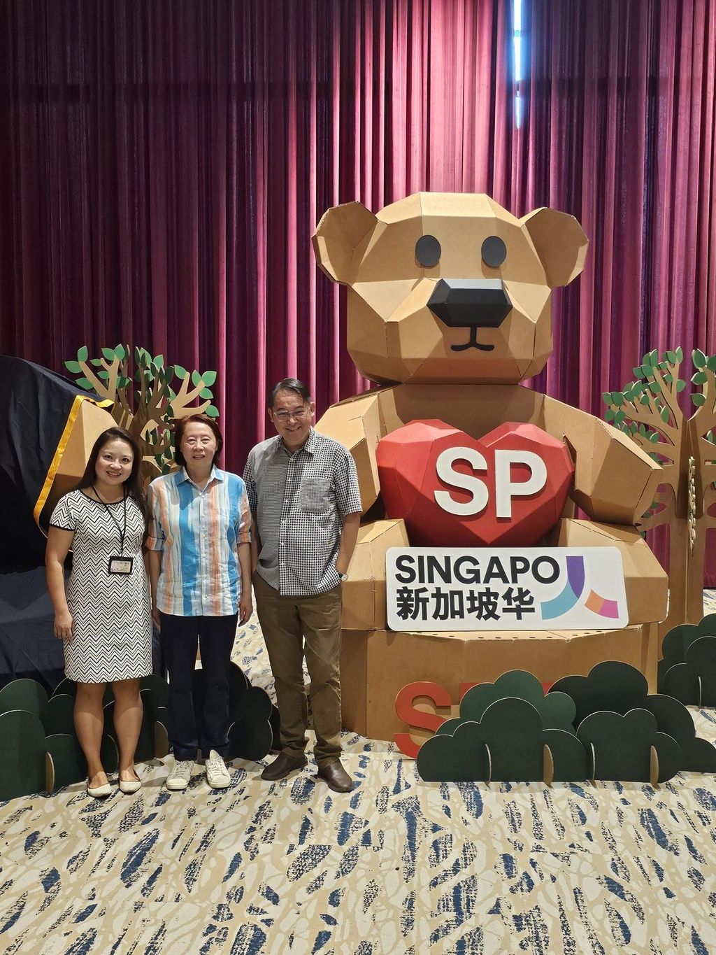 Three project collaborators standing beside the SP graduation bear