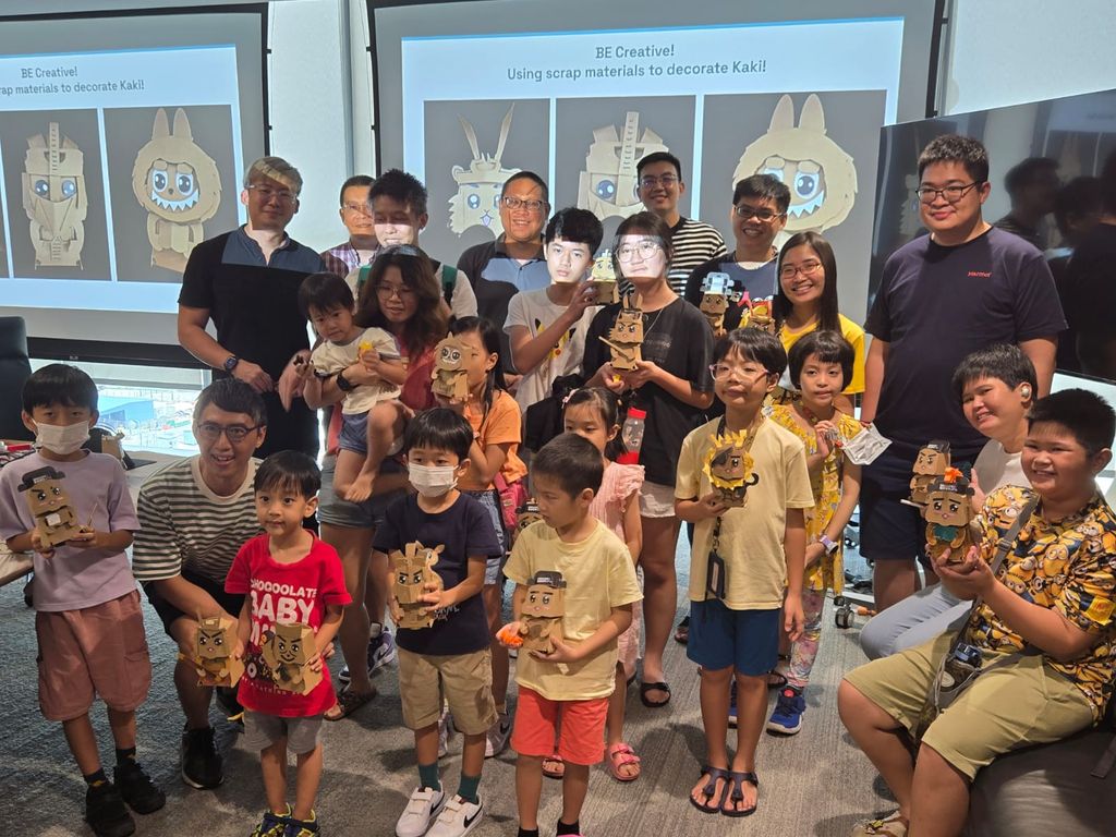 Children, families, and facilitators holding their completed cardboard robots