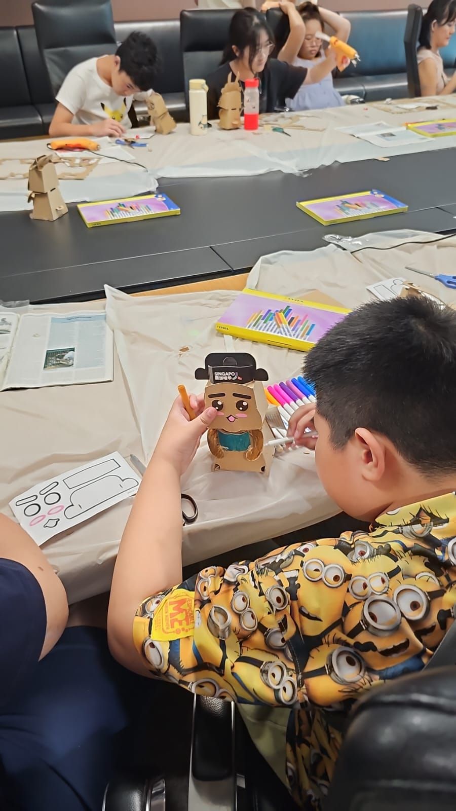A child adding details to a small cardboard robot during the workshop