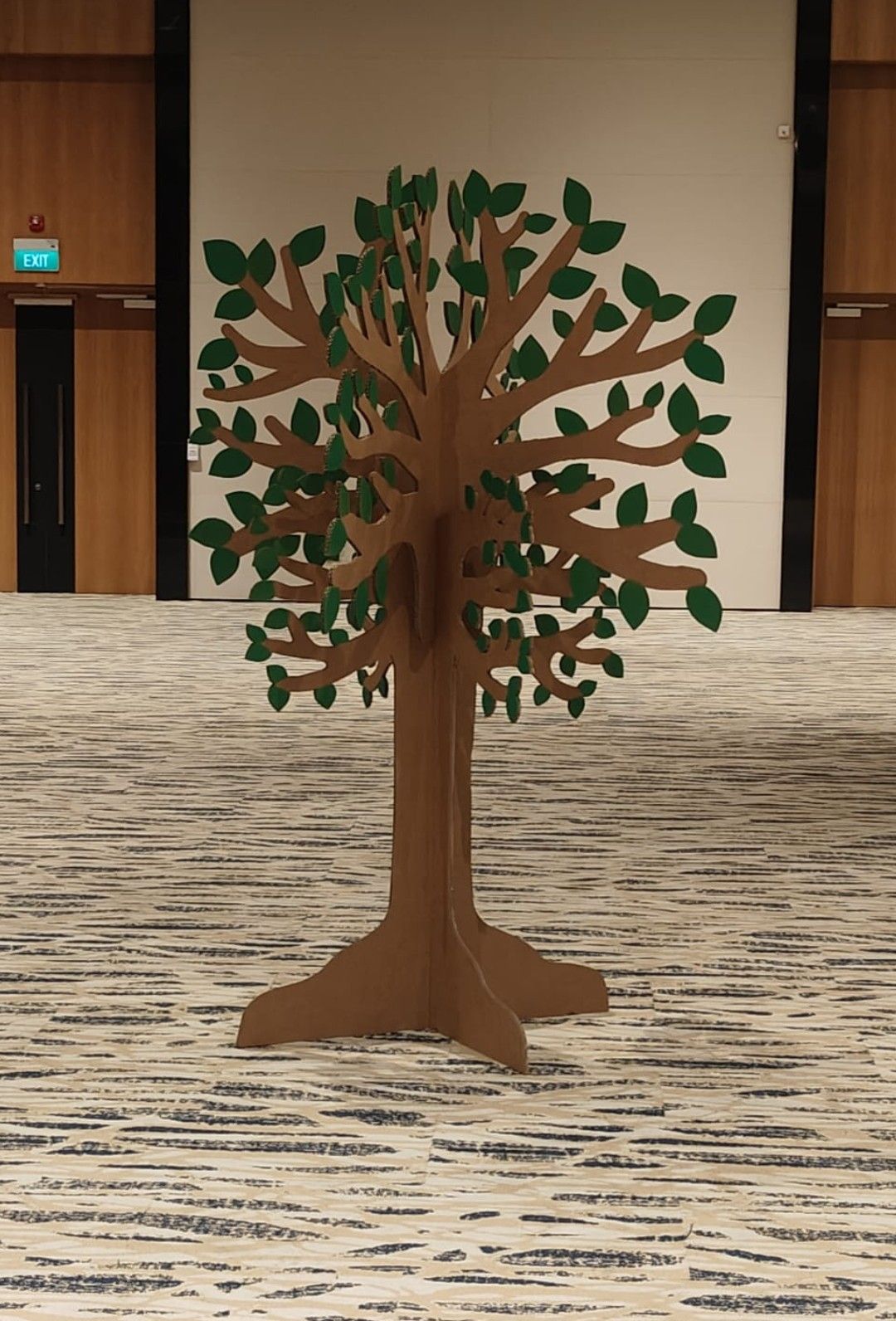 A finished cardboard tree with layered brown branches and green leaves