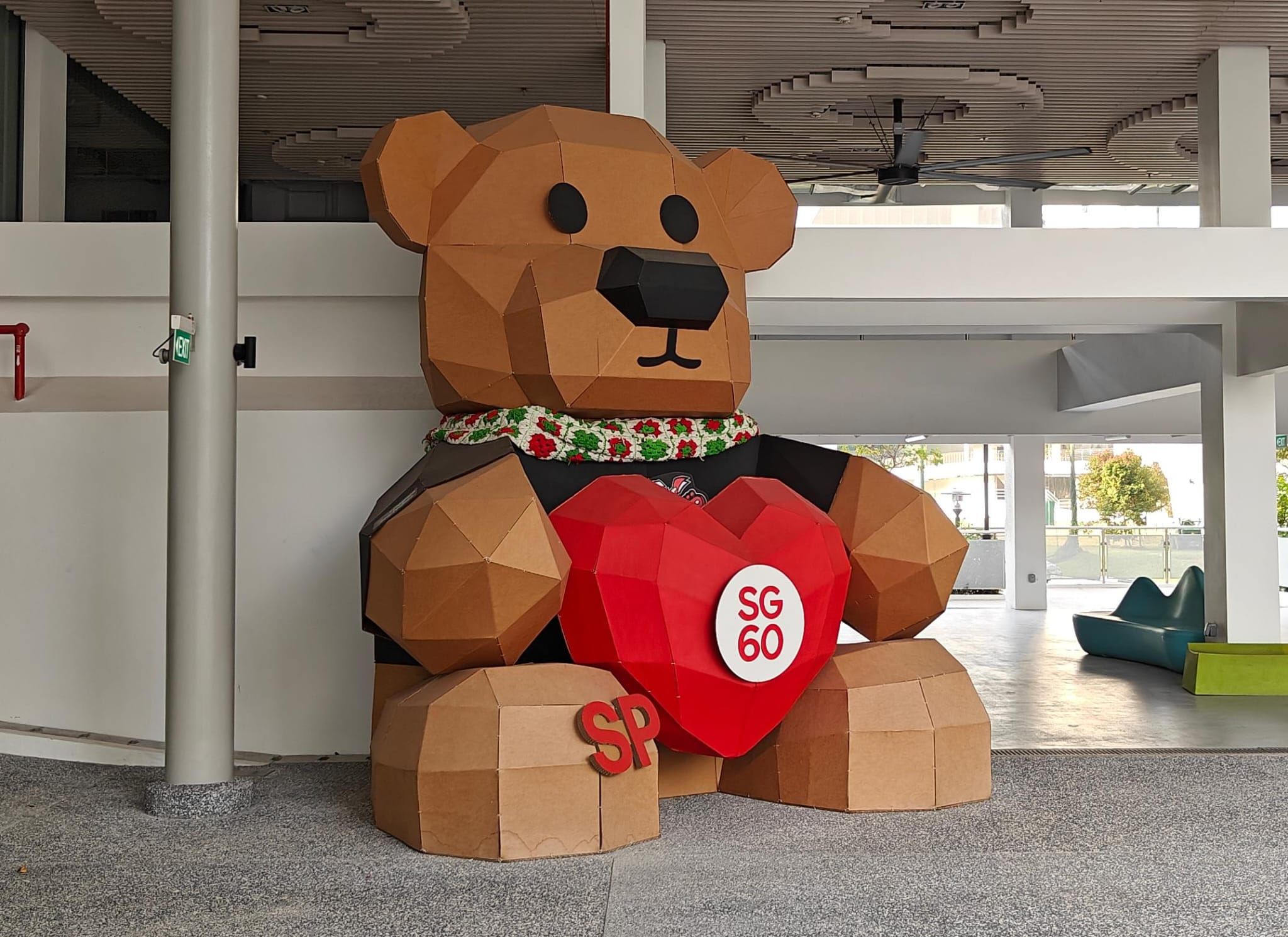 Completed low-poly cardboard bear holding an SG60 heart inside the Fablab