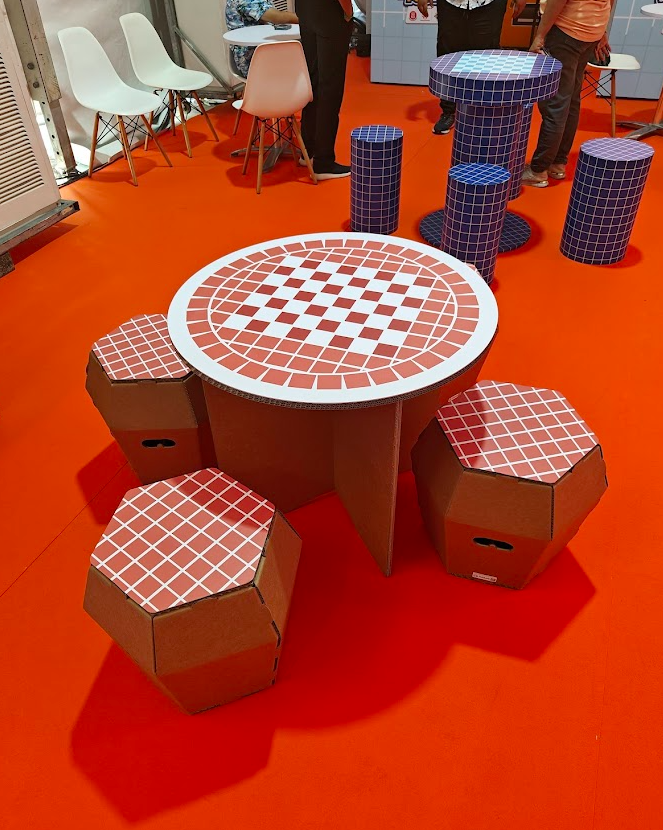 Completed cardboard table and stools finished with red-and-white grid patterns