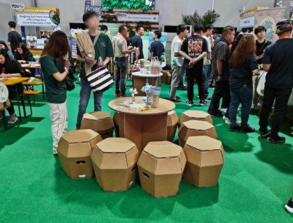Visitors gathering around circular cardboard tables and stools at the launch