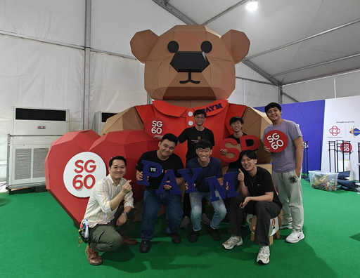 Fabrication team gathered beside the SG60 bear holding red heart signs