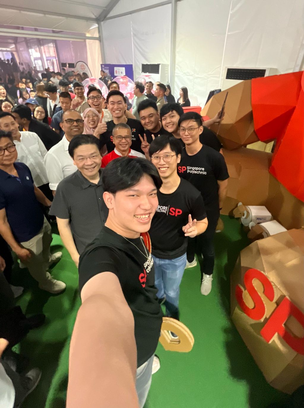 Student team taking a celebratory selfie beside the large cardboard bear