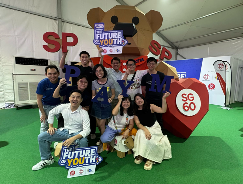 Project team posing with SP and PAYM letters at the Future of Youth installation