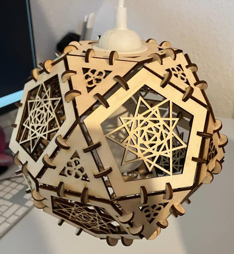 The finished lamp shade is made from triangles and pentagons in a roughly ball shape