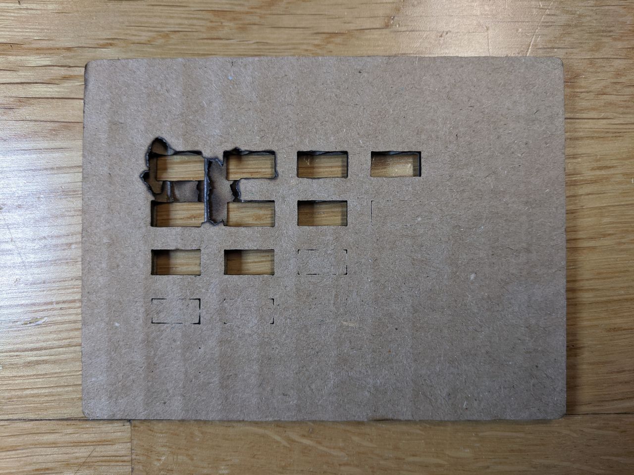 Back of cardboard laser test showing burnt spot.