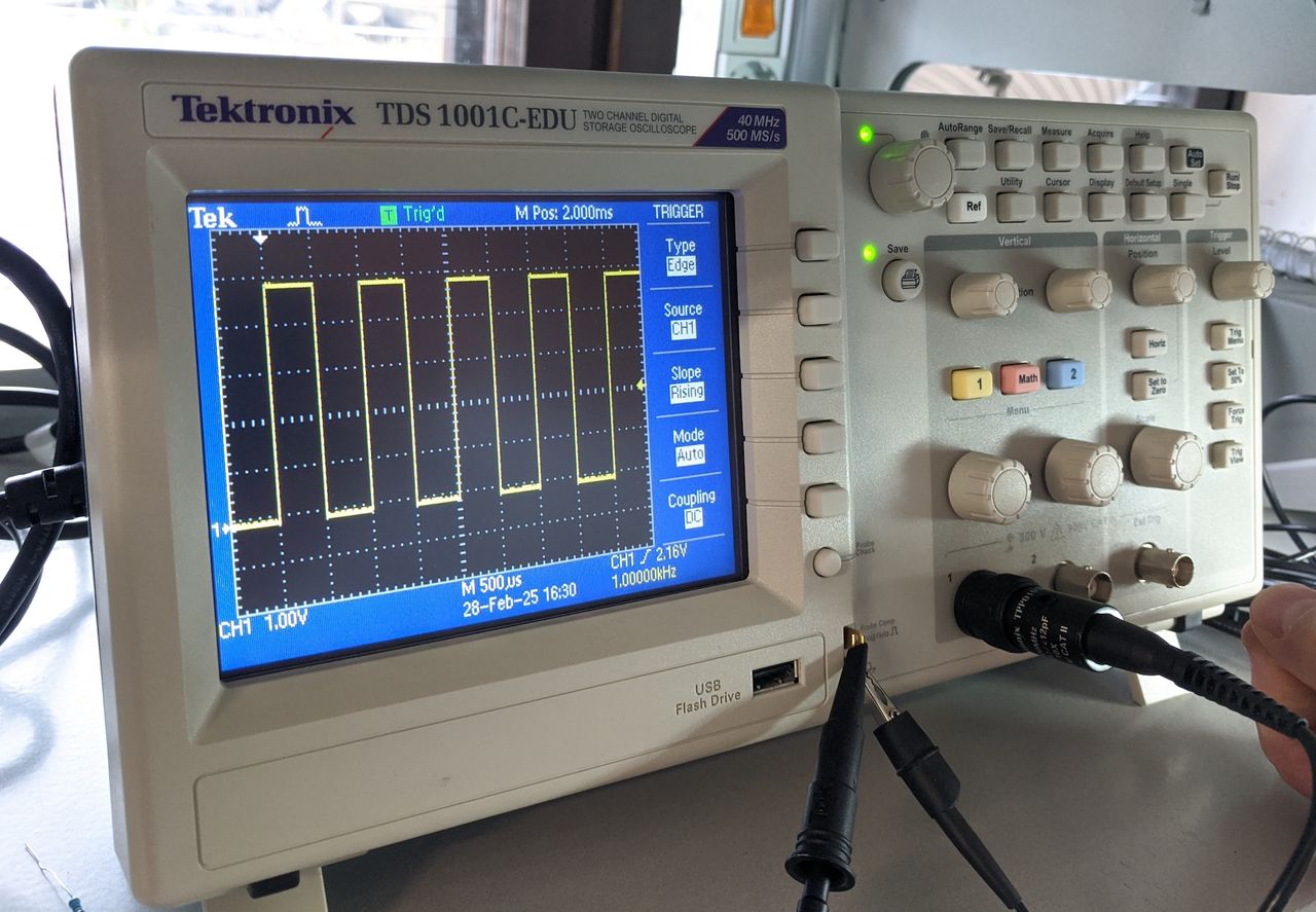 Oscilloscope with screen showing the test square wave.