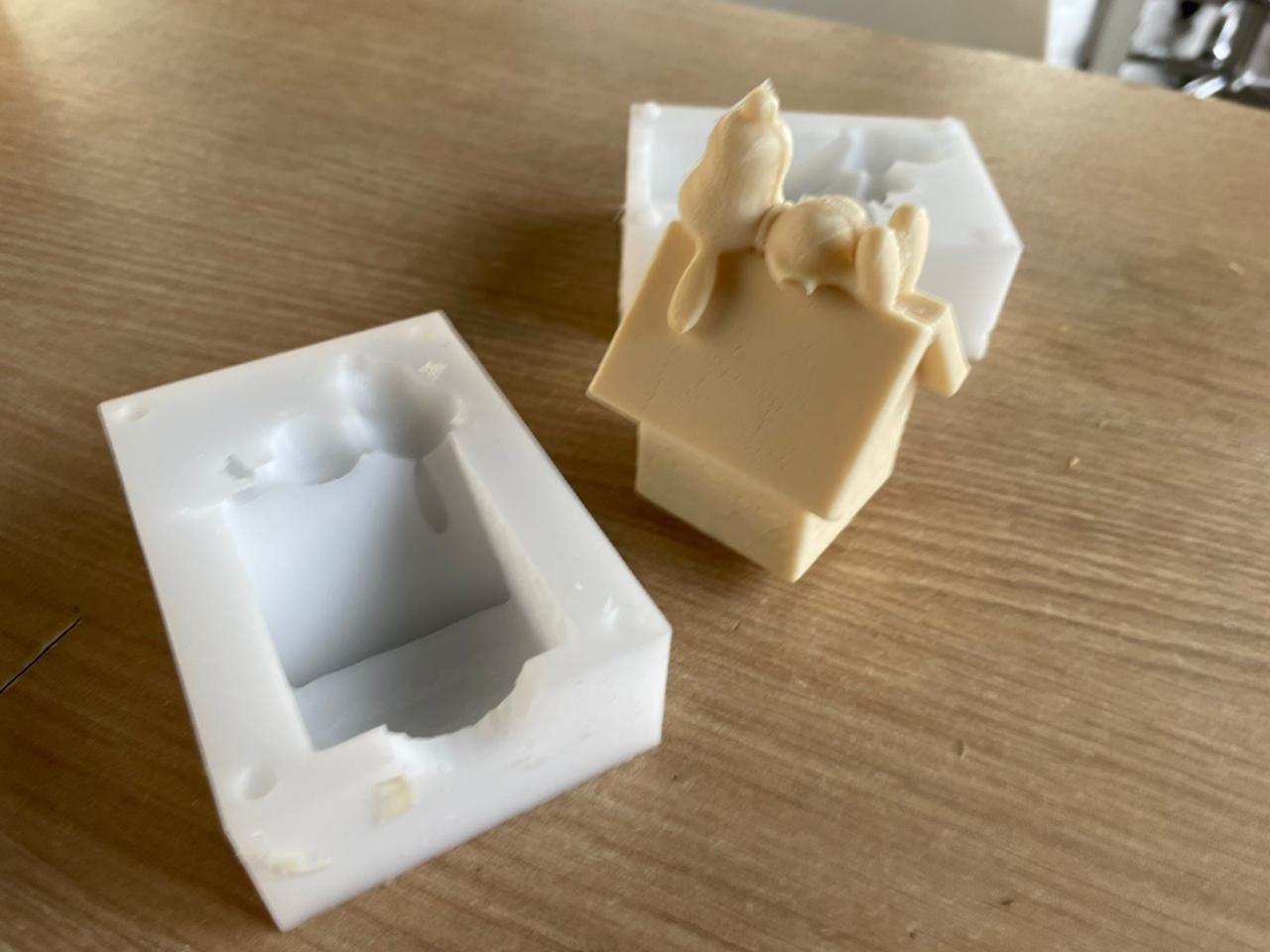 Final result — white silicone mold open alongside the cured cast part of the doghouse