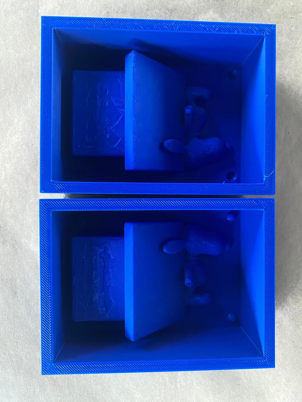 Two 3D-printed blue mold containers — both halves open showing the interior geometry