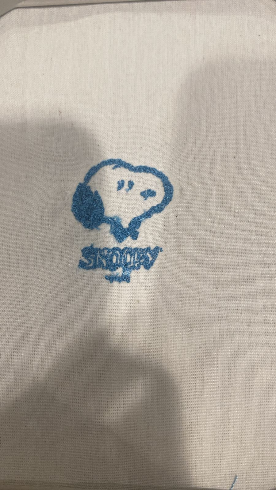 Final embroidery result — Snoopy in blue thread on white linen