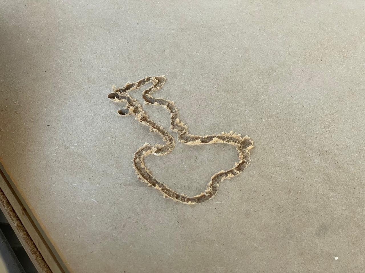 First test of the Snoopy silhouette cut in MDF — profile result with frayed edges visible