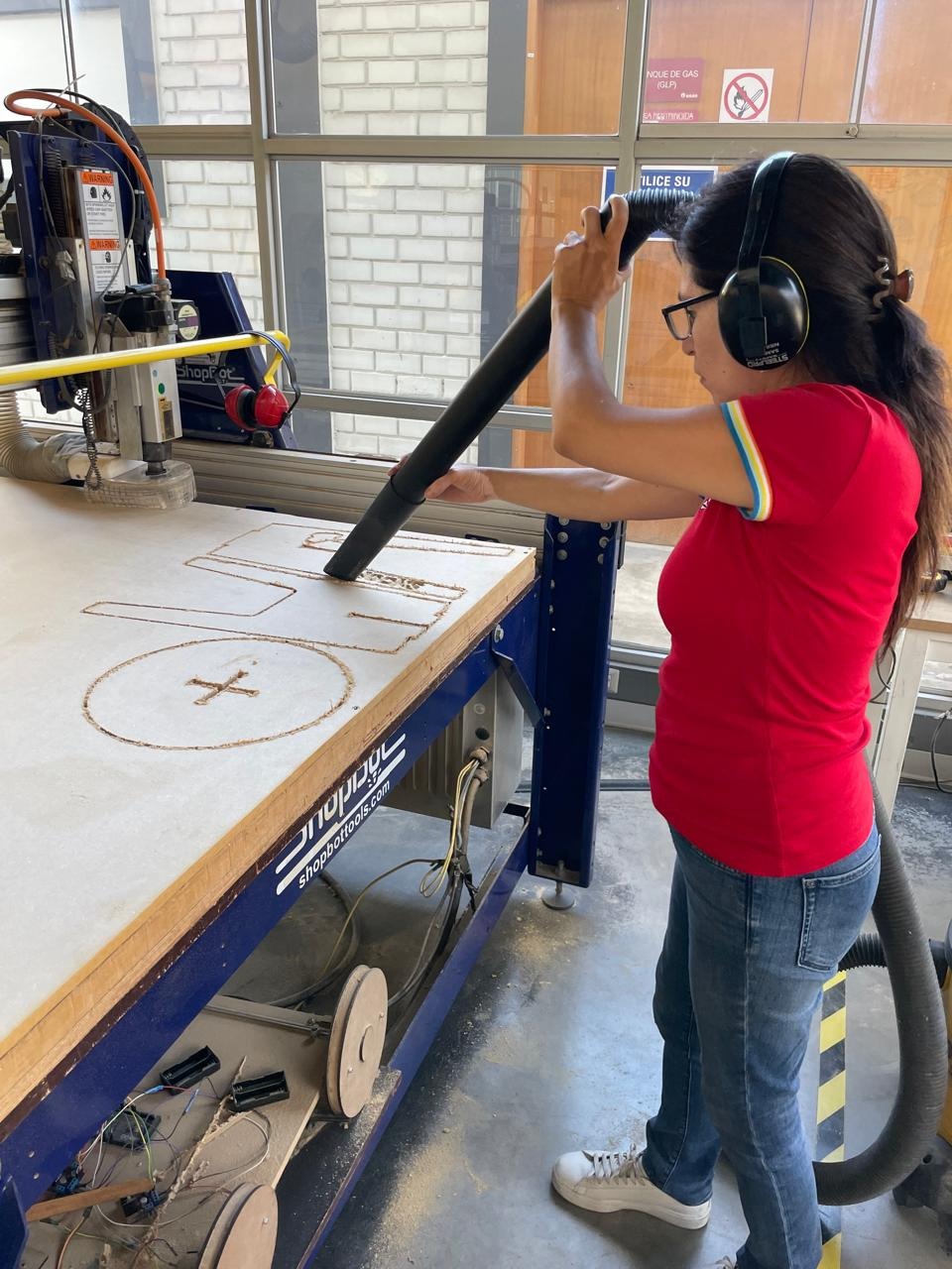 Marita vacuuming MDF dust from the ShopBot bed between toolpaths