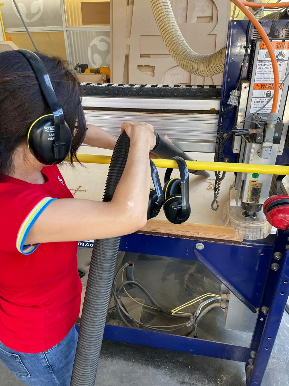 Vacuuming the ShopBot bed with a shop vacuum — wearing ear protection