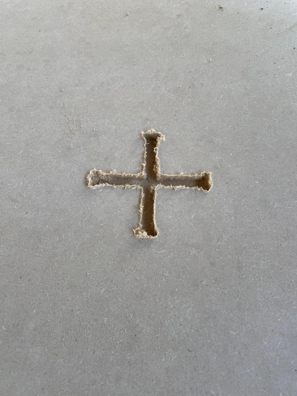 Close-up of the T-Bone cross slot cut into the MDF — the four rounded overcuts at each corner are clearly visible