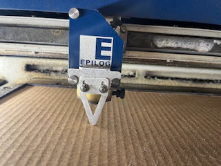 Metal focusing tool touching cardboard on the laser cutter head