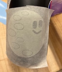 Moon sticker on water bottle with transfer paper over it.