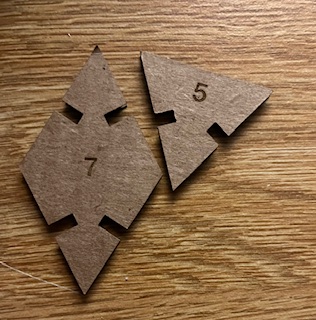 A cardboard diamond and a triangle with a 7 and 5 engraved respectively