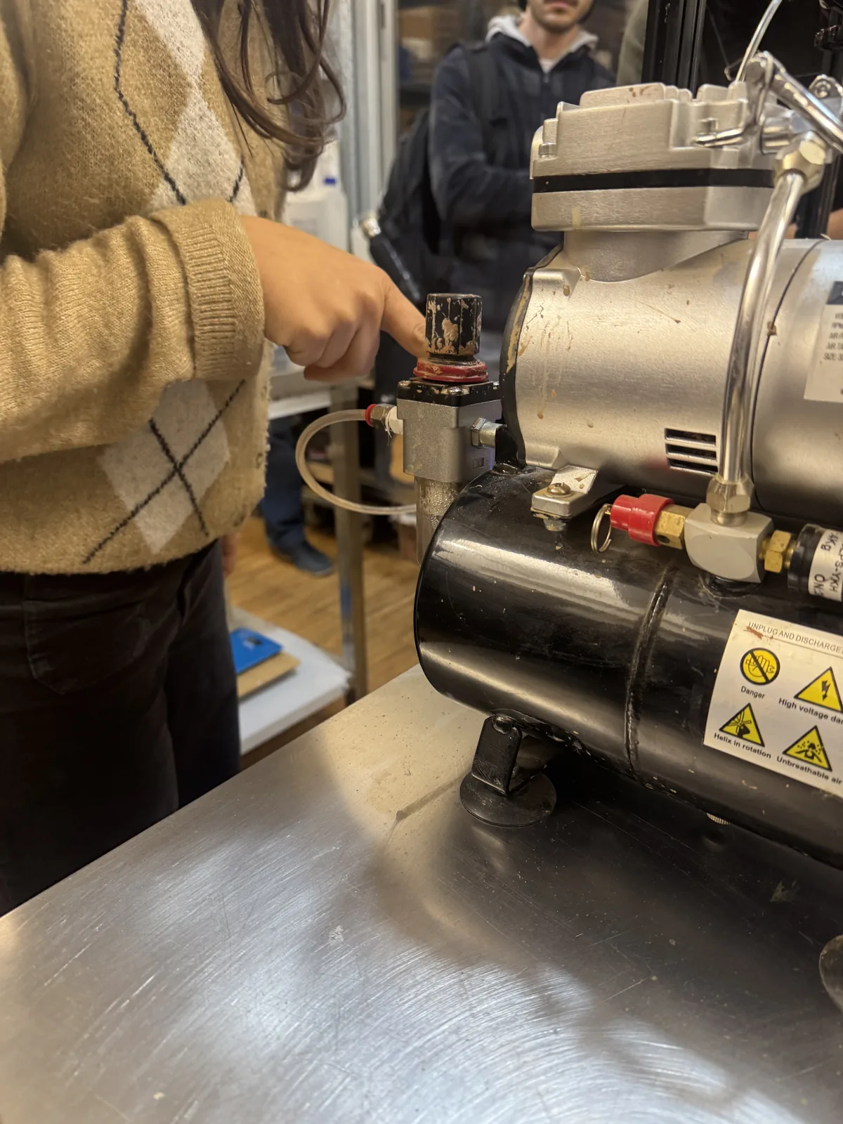 Hand adjusting an air compressor and pressure tank feeding the clay extruder