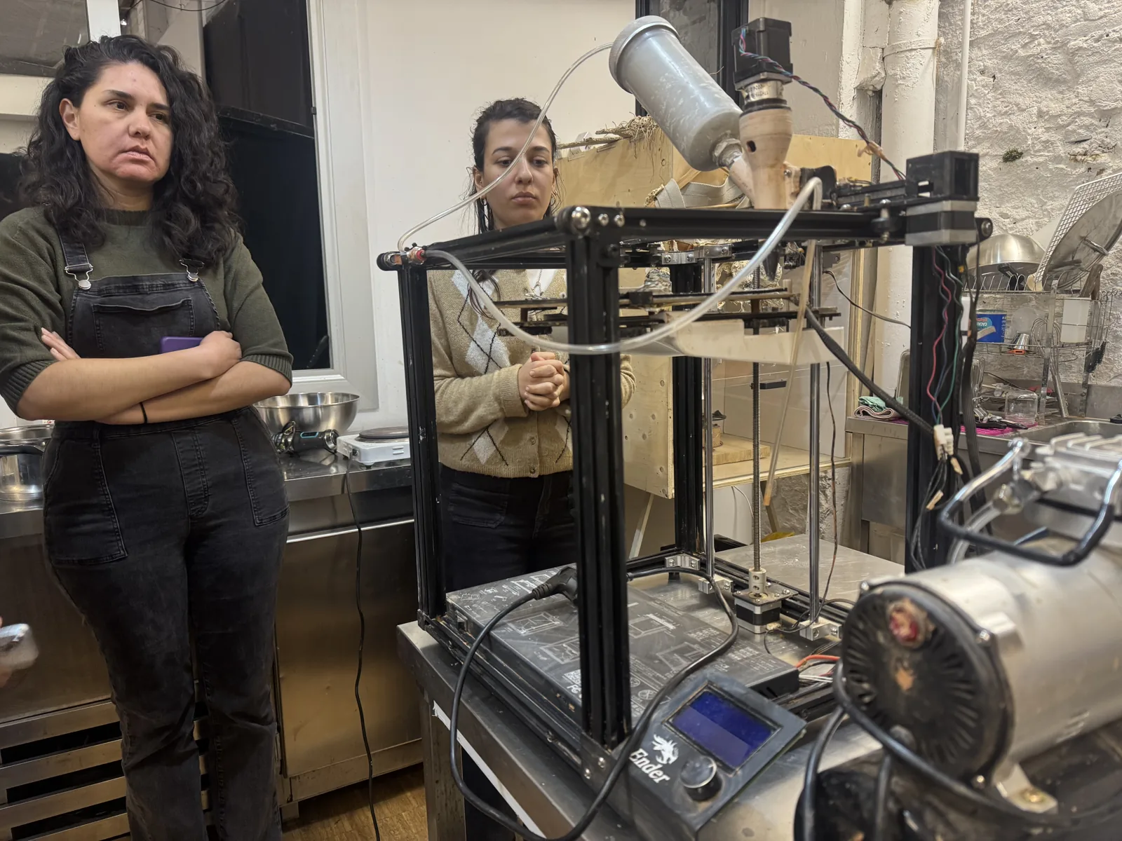 Large clay paste extrusion printer with an aluminium clay reservoir, two people observing