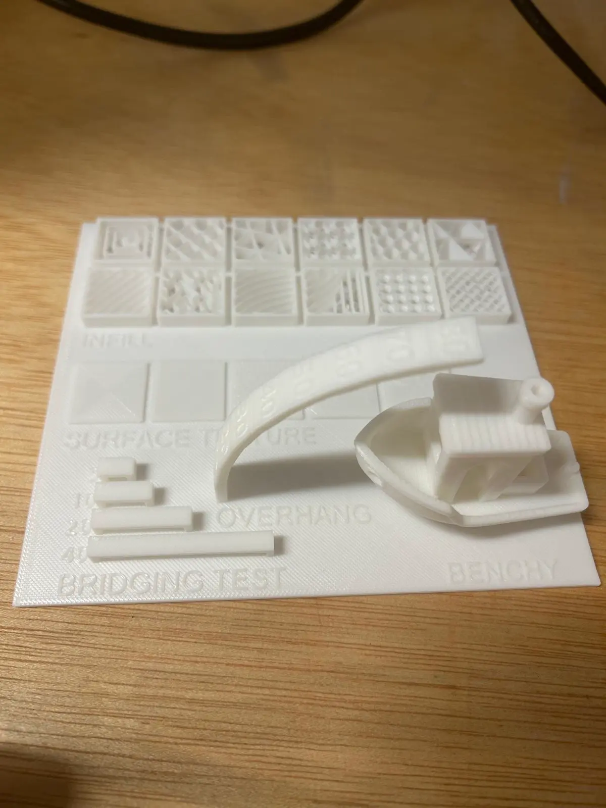 Completed capability test print showing infill patterns, surface textures, bridging test, overhang arc, and benchy boat