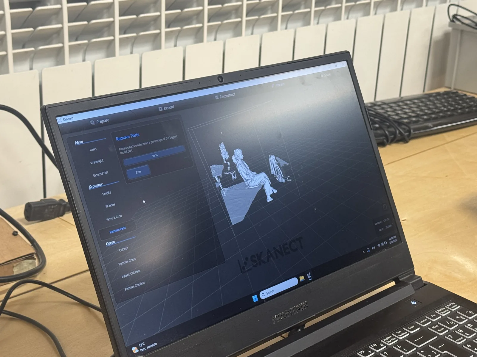 Laptop running Skanect showing a 3D scan of a seated person in the Prepare / Remove Parts stage