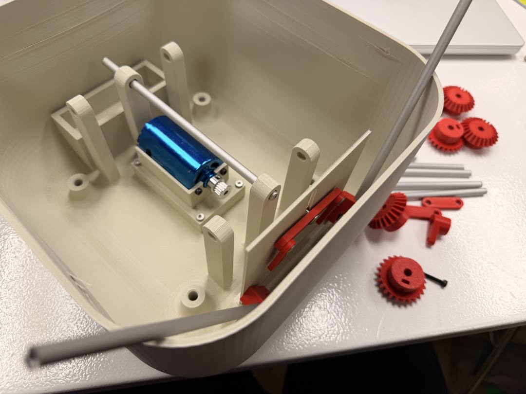 Creature body with motor and axle supports installed, gears and other parts laid out beside it