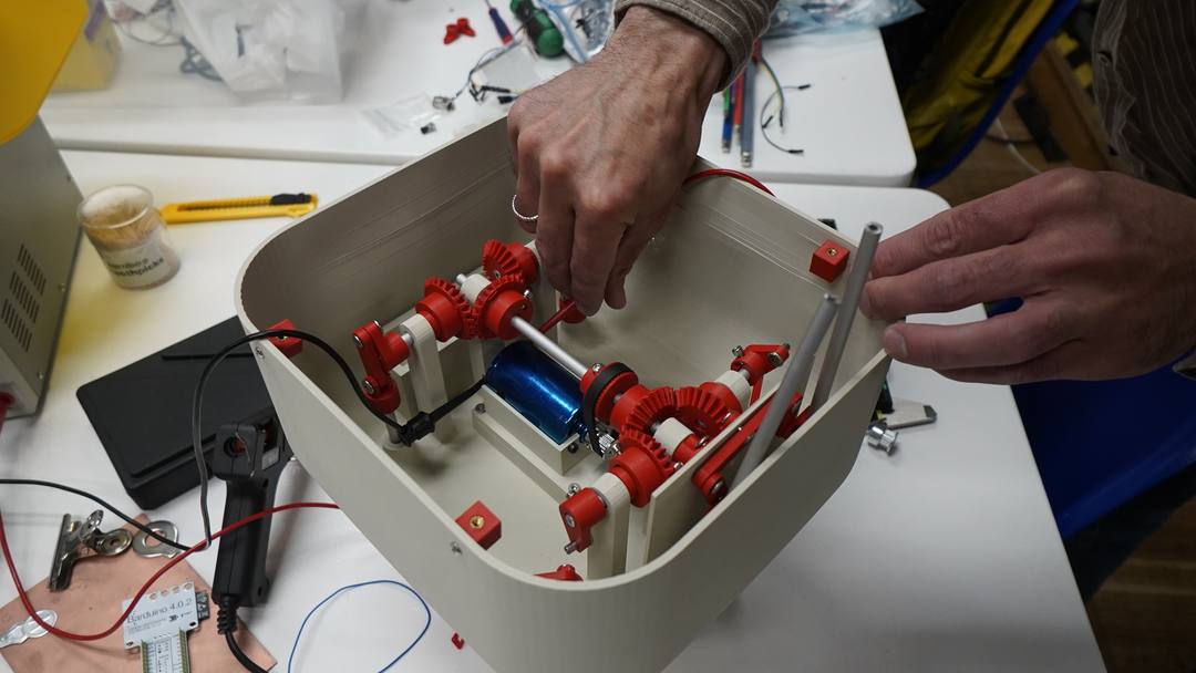 Hands installing bevel gears and linkages inside the body