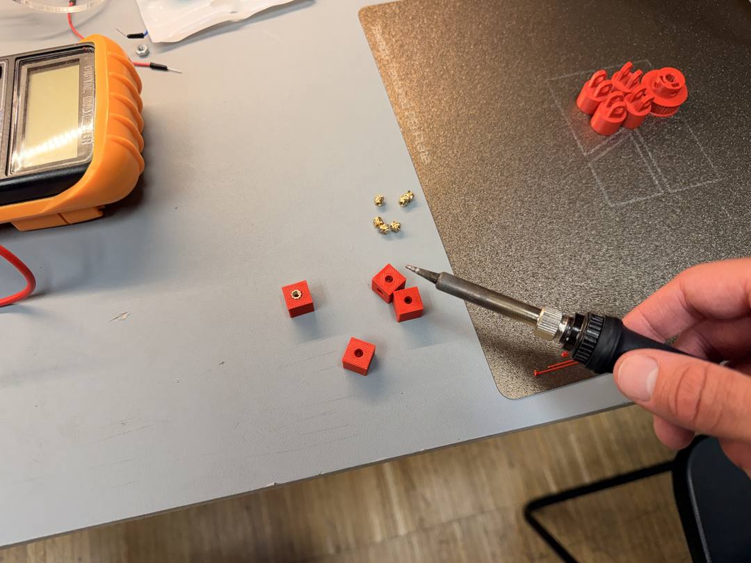 Soldering iron pressing heat-set threaded inserts into 3D printed lid mounts