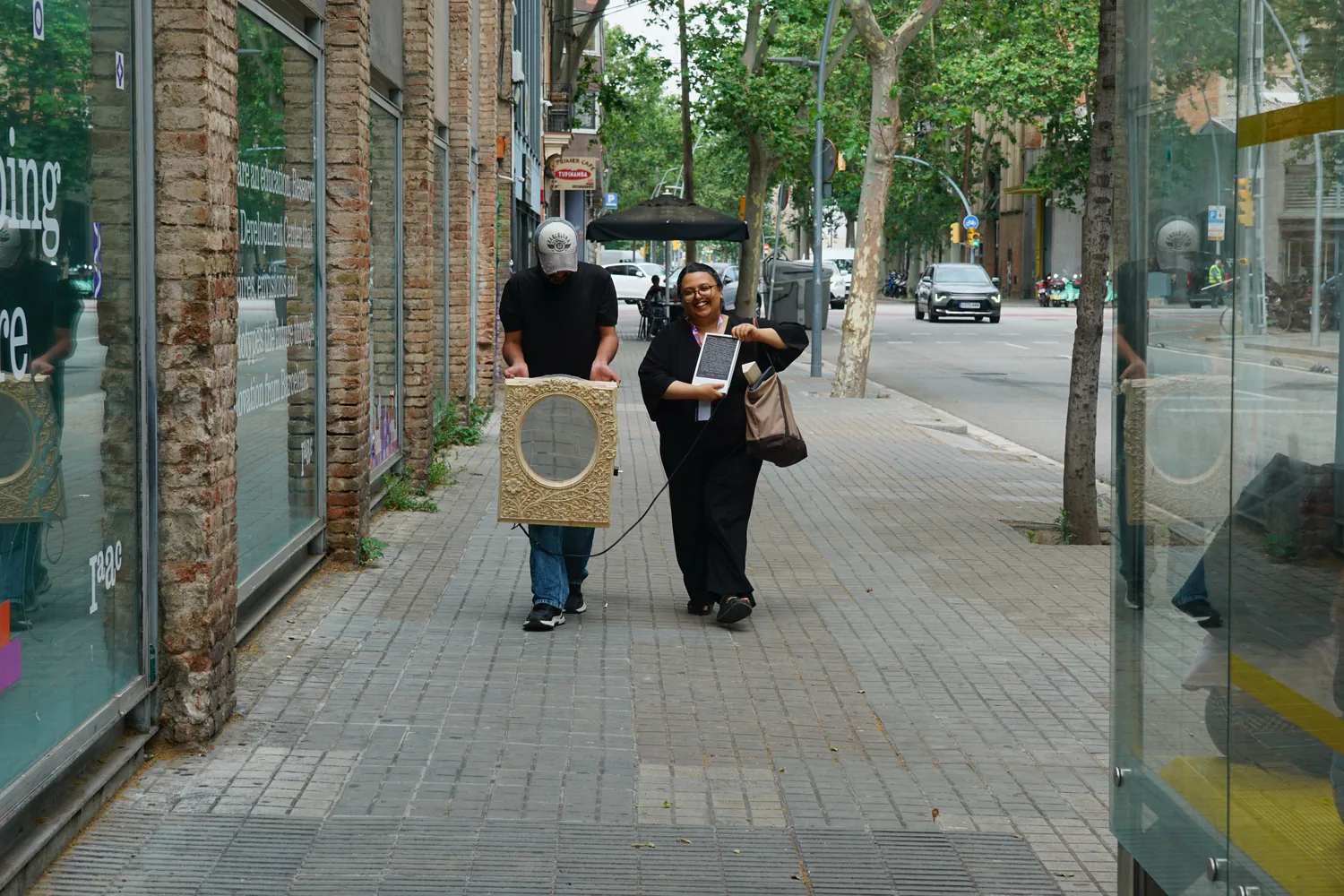 Two people carrying the finished mirror down a Barcelona street toward the IAAC exhibition