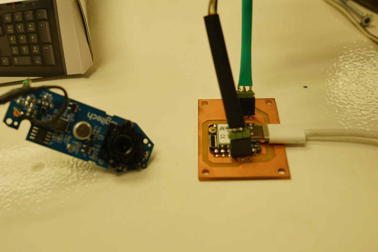 Bring-up bench: a disassembled Logitech webcam beside the copper XIAO board wired up with a USB cable