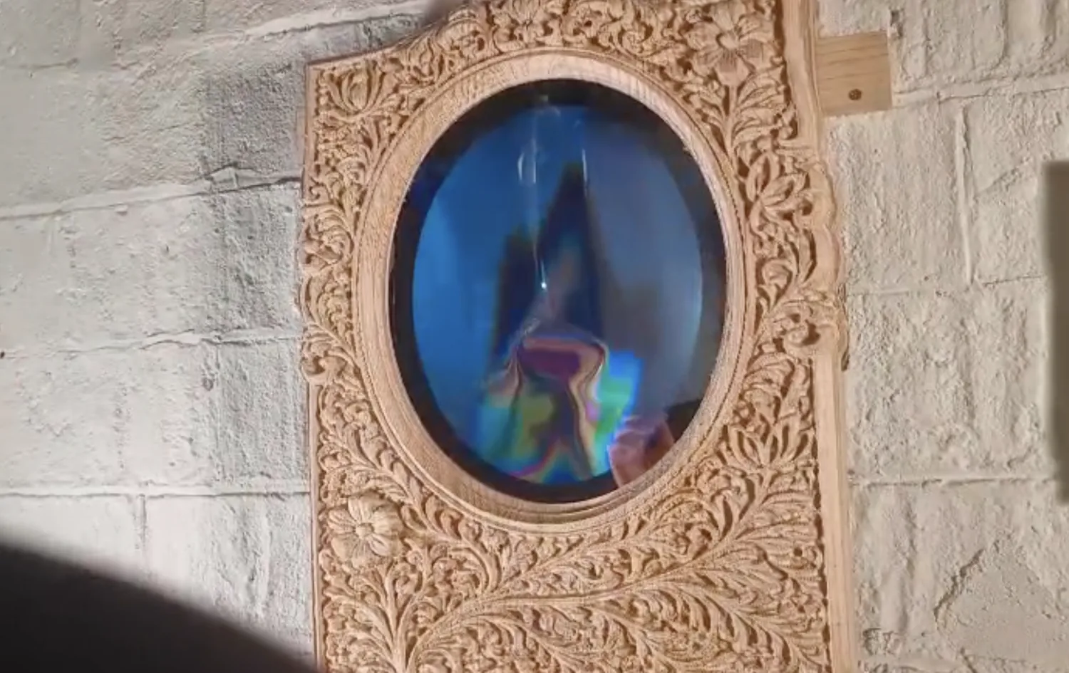 The reflection warping into chromatic distortion inside the oval