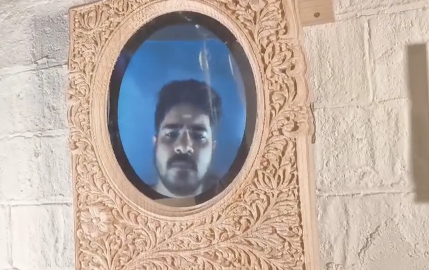 A viewer's face reflected clearly in the oval mirror