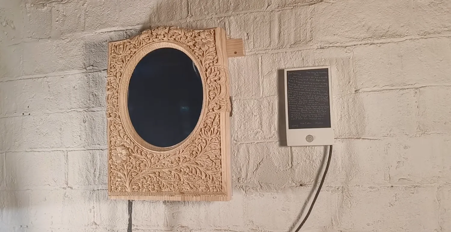 The piece at rest on the wall: the oval reads as a dark mirror, the letter unlit beside it with the PIR dome visible