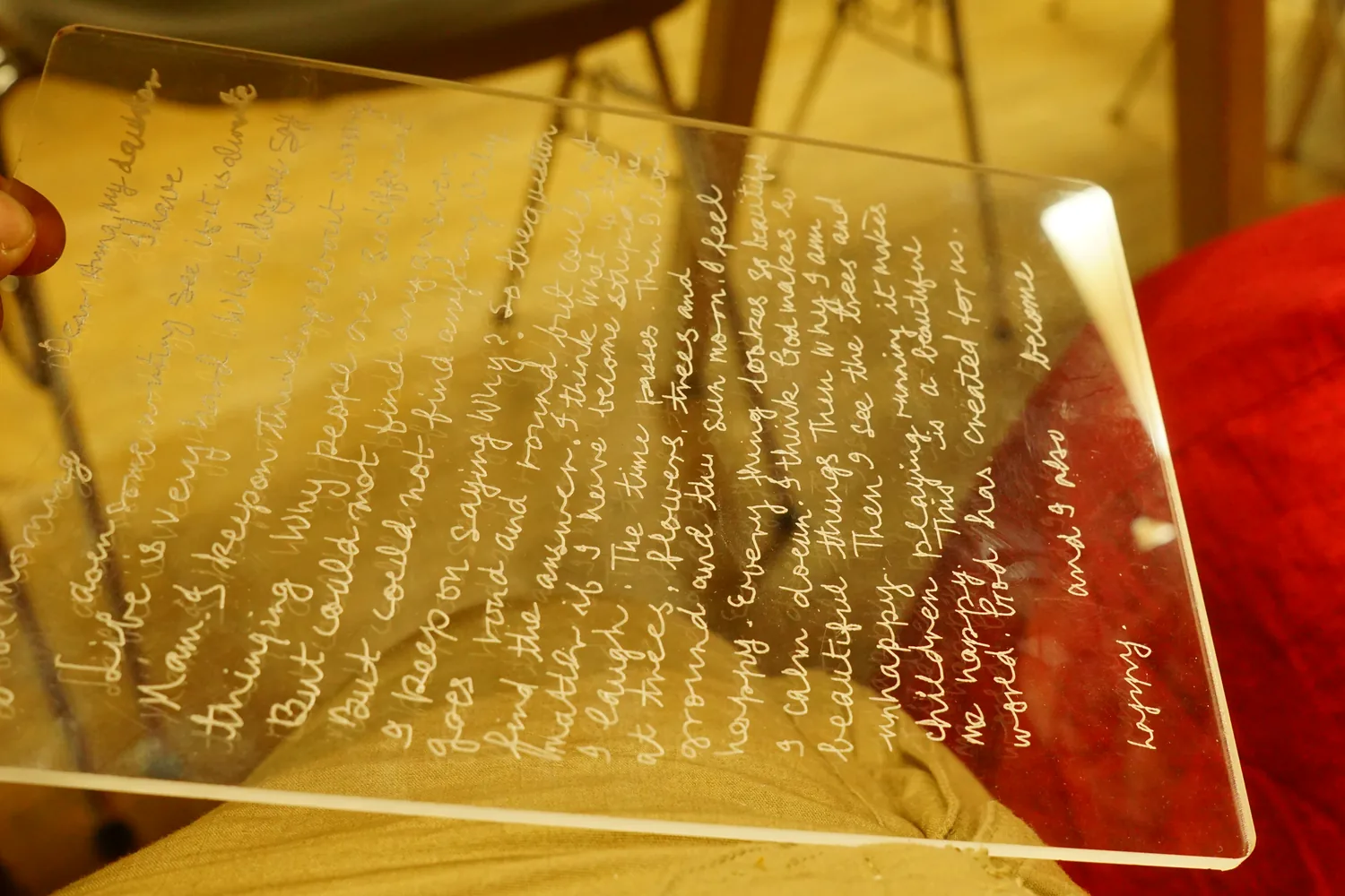 Maya's handwritten letter, centerline-traced and laser-marked into a clear acrylic sheet, held up to the light