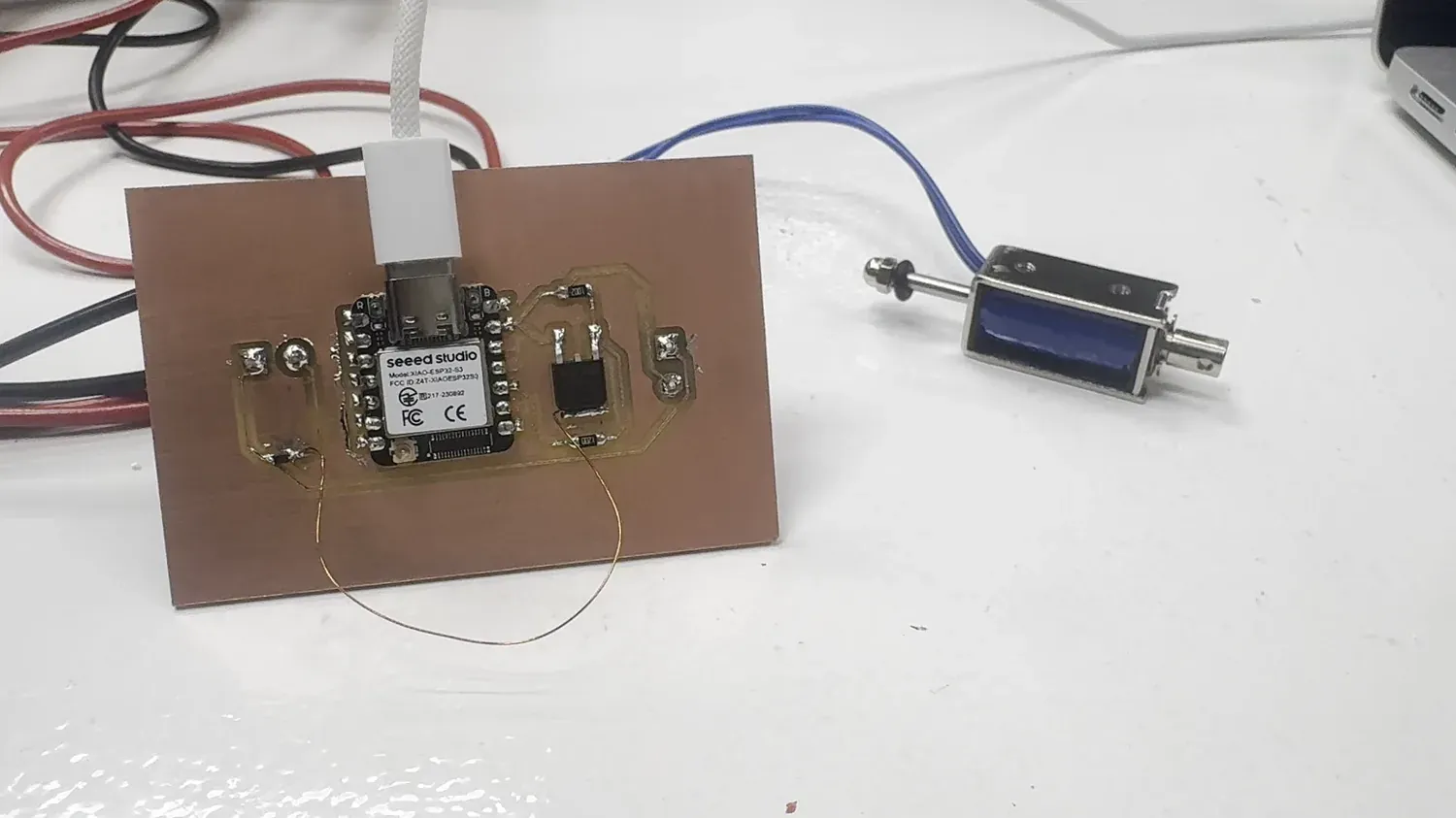 The milled copper XIAO ESP32-S3 board wired to a 12V solenoid — the networked node and its output device
