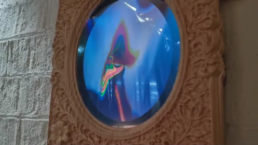 The reflection warping into chromatic distortion inside the oval
