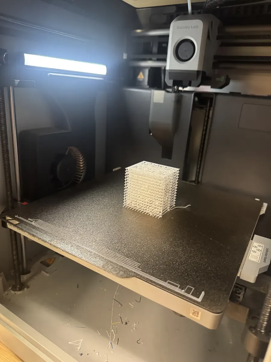 Lattice cube mid-print on FDM printer showing stringy failed geometry