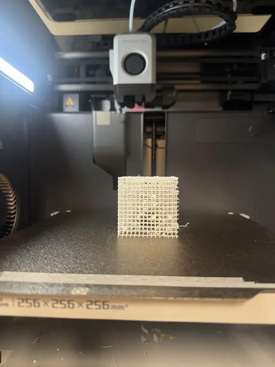 Failed FDM print of lattice cube showing collapsed geometry and stringing