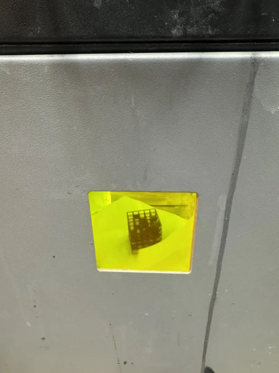 Lattice cube visible through the yellow UV-filtering window mid-print