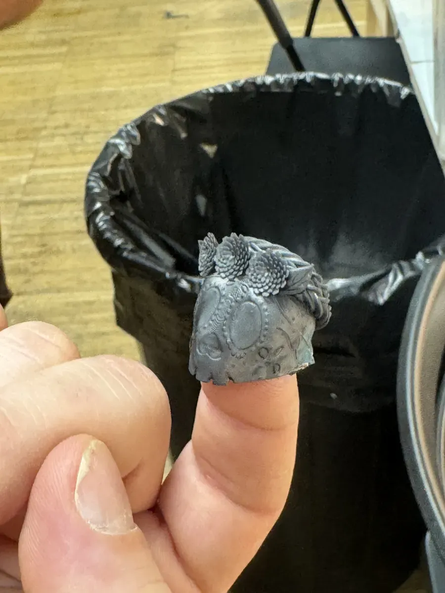 Tiny resin-printed Day of the Dead mask held on fingertip