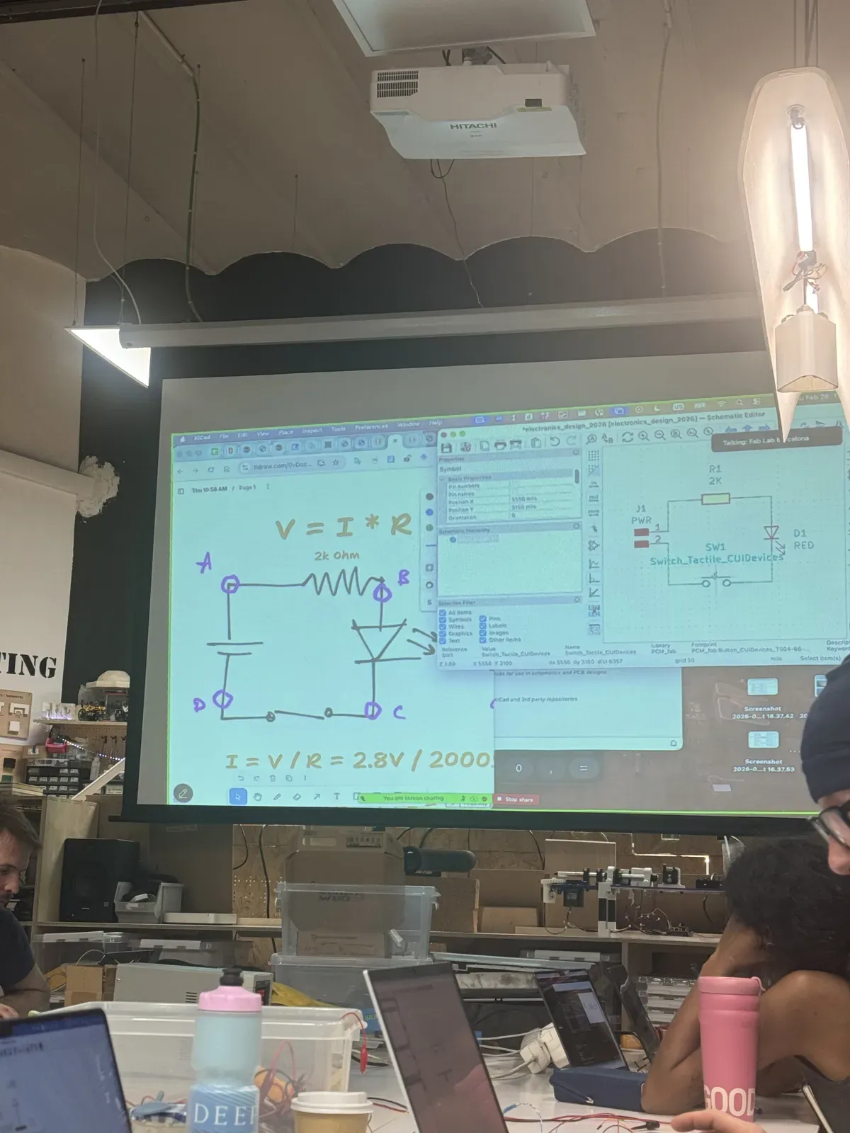 Fab Lab classroom with Ohm's Law V=IR drawn on projector alongside KiCad schematic editor