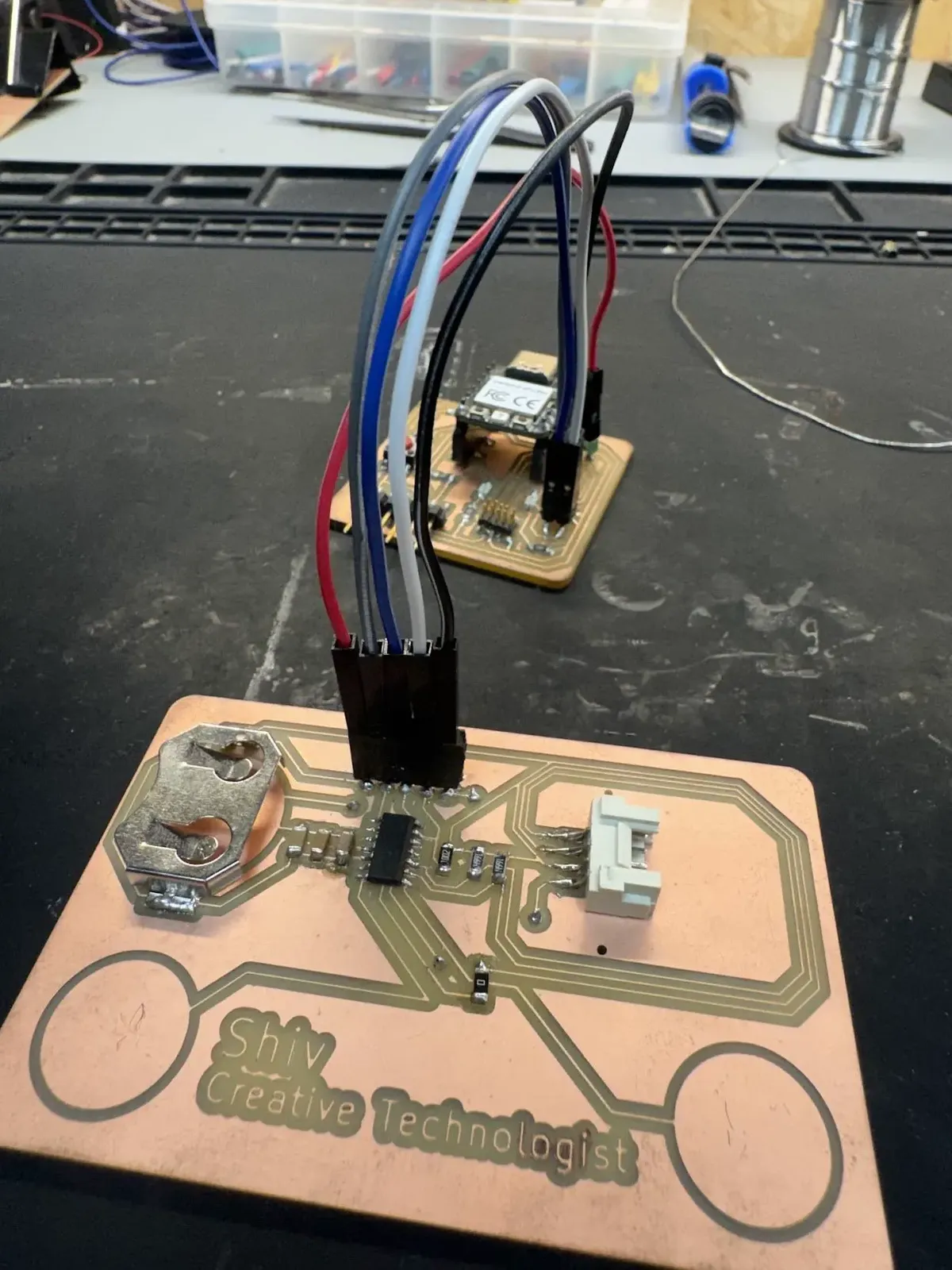 PCB business card fully soldered, ATSAMD11C14A, OLED connector, CR2032 holder, Shiv / Creative Technologist in copper, connected to Quentorres SWD programmer